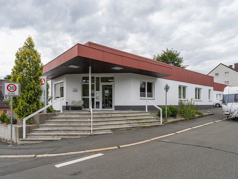 Flaches Gebäude der Agentur für Arbeit mit rotem Dachrand, Treppe und Eingangsschild