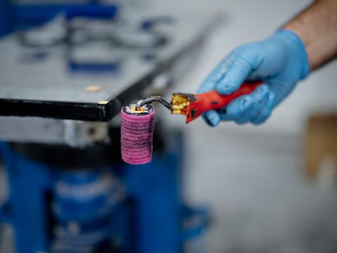 Hand im blauen Handschuh hält eine gebrauchte Farbrolle in einer Werkstatt