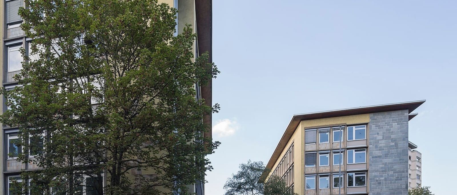 Zwei Bürogebäude eines Finanzamts in Köln mit Bäumen und Straße im Vordergrund