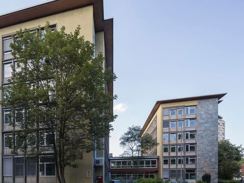 Zwei Bürogebäude eines Finanzamts in Köln mit Bäumen und Straße im Vordergrund