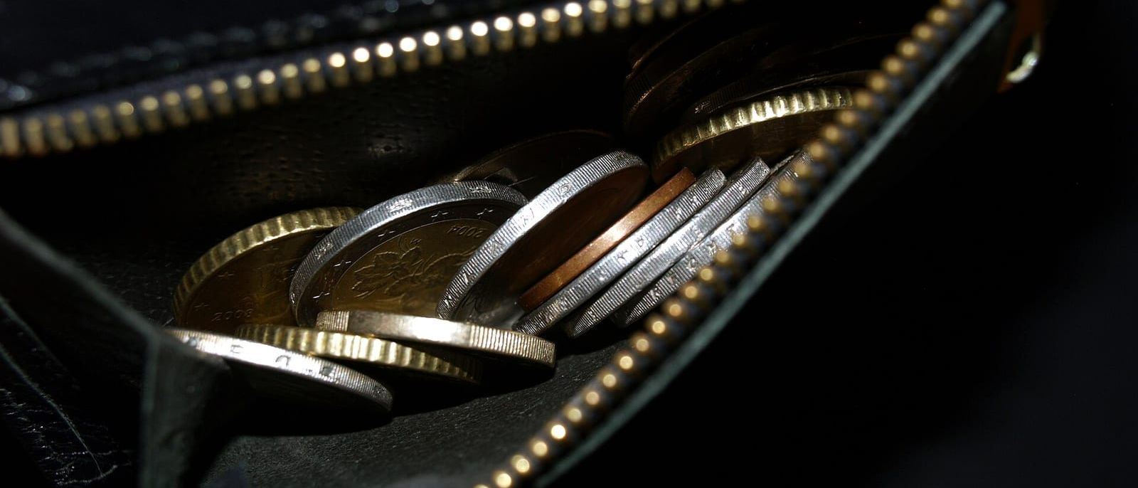 Euro-Münzen in einem geöffneten schwarzen Portemonnaie mit Reißverschluss